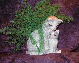A gray/white glazed, ceramic mama cat with kitten and air fern.