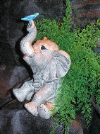 Gray glazed, ceramic sitting elephant with butterfly on upward trunk and air fern.