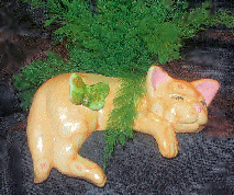 A yellow glazed, ceramic sleeping shelf cat with air fern.