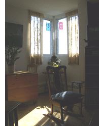 This is the southeast corner of the living room. It's sunny and warm all the time. In winter, I put the leaf up on the old table and work here, with the sun beating on my back, or pull a rocking chair over and read. It's a nice corner.