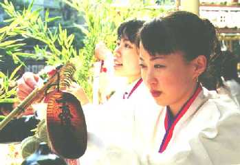 Priest-girls attaching lucky token to bamboo branches at Ebisu festival