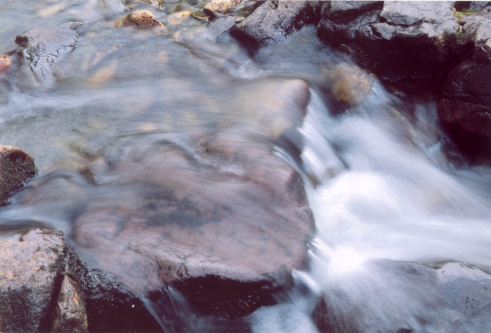 Crystal clear water slowly flowing over a smooth stone
