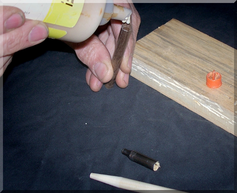 An image of a man adding glue to the hollow center of a wooden dowel, beside an arrowhead removed from a broken arrow.