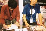 Ueda Yasuyuki & Abe Yoshitoshi, producer/creator & character designer (respectively) for SERIAL EXPERIMENTS LAIN, autographing my Lain cel and a shikishi from HAIBANE RENMEI (which Abe also created)