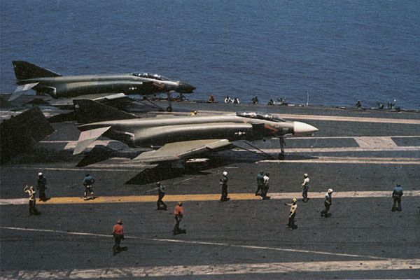 Adorned in experimental camouflage paint, two VF-213 Phantoms, an F-4G and an F-4B, prepare for launching from the USS Kitty Hawk off Vietnam in 1966.