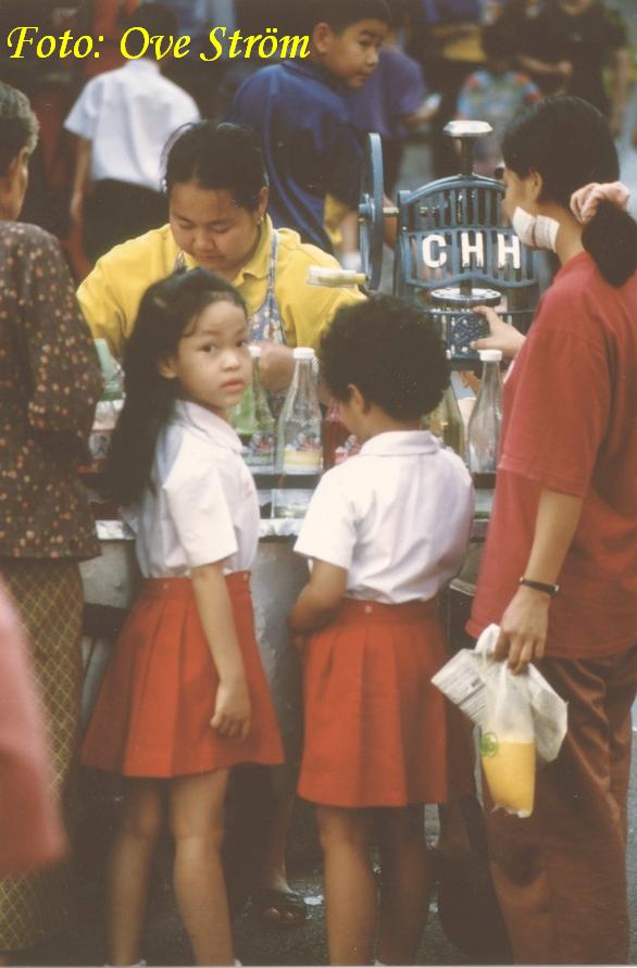 En glassf�rs�ljerska och sugna barn i Bangkok. Observera glassmaskinen d�r hon river is som sedan blandas med saft. Foto: Ove Str�m
