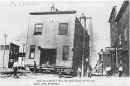 ImageLink to Fullsize Early photo of Gilbert's first City Hall being moved into place down Broadway.