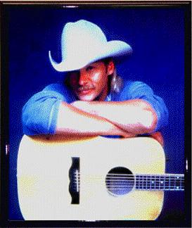 Alan Jackson in blue leaning on guitar