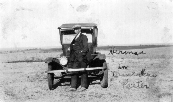 Here is Herman standing behind the front bumber of a ford.