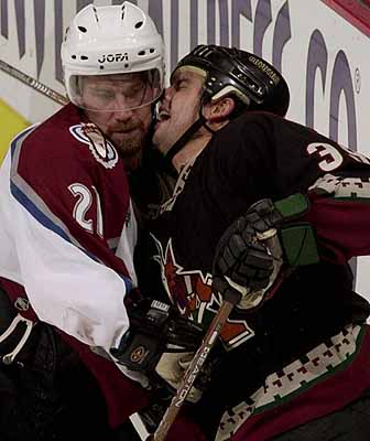 Colorado Avalanche center Peter Forsberg, left, runs Phoenix Coyotes center Travis Green into the boards in the third period of the Coyotes' 4-0 victory in Denver's Pepsi Center on Monday, Oct. 30, 2000. ( Photo/Bryan Kelsen) 