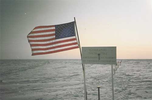 American flag and sign indicate locaton of the latest survey marker for the geographic south pole