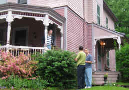 Friends chat off the side of a lavender Queen Anne porch