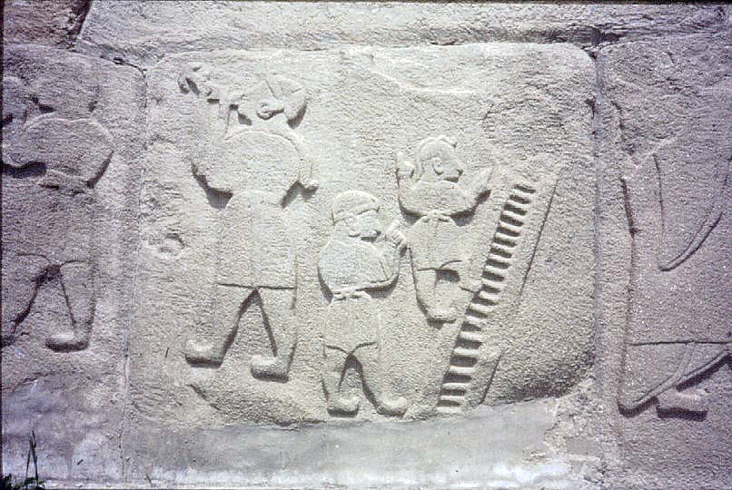 Akrobate uklesane na vratima grada. Gutac vatre levo i akrobata na merdevinama.