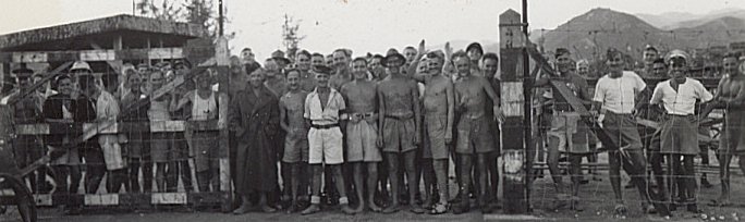 Men at gate of POW camp, Kowloon