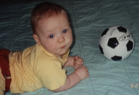 Jason laying on the floor, playing with his soccer ball--8 months old