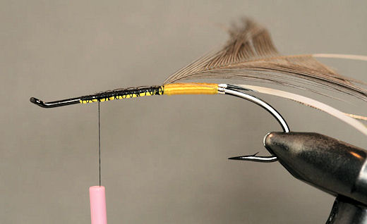 Stroke the fibers of the feather back and tie it in by the tip. And clip off the excess.